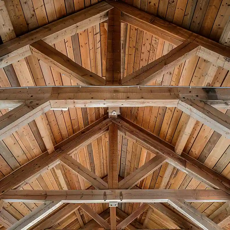 Traitement charpente 41 Vue d'un plafond en bois avec des poutres et des fermes apparentes, mettant en valeur le grain naturel du bois et les motifs géométriques - une inspiration idéale pour le traitement charpente dans le 41.
